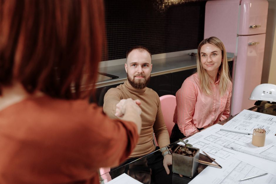 Business professionals sitting around a table during a planning session, engaging in a handshake.