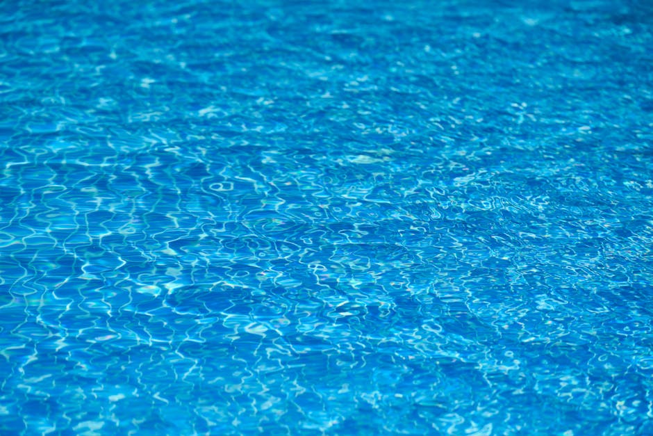 Bright and clear blue water texture in a swimming pool under sunlight.