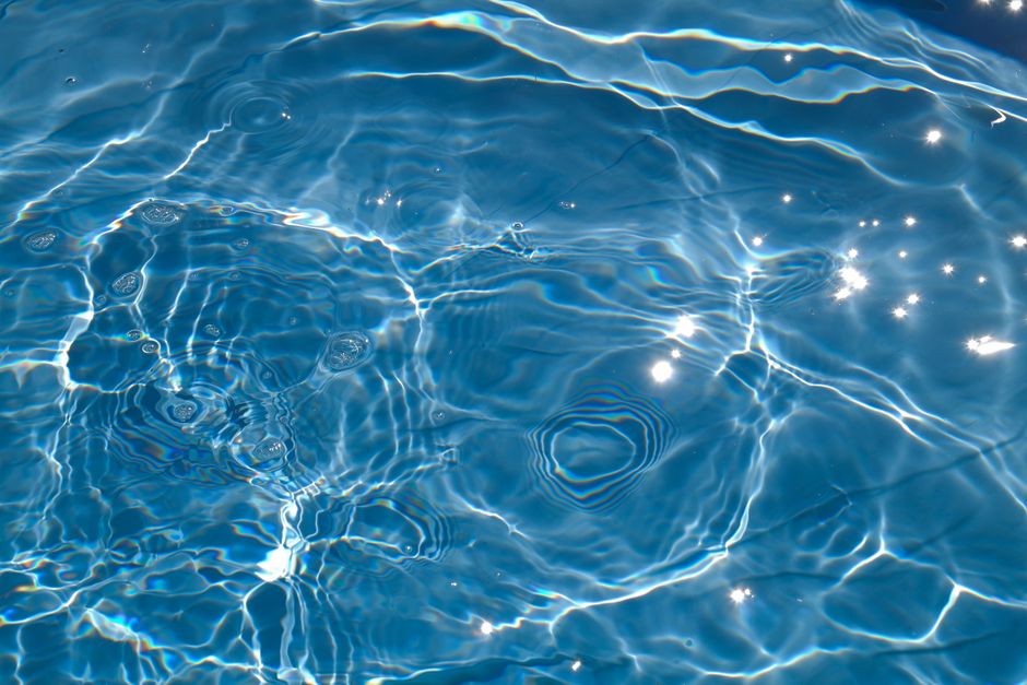 Close-up of sparkling pool water with sunlight reflections creating a vibrant pattern.